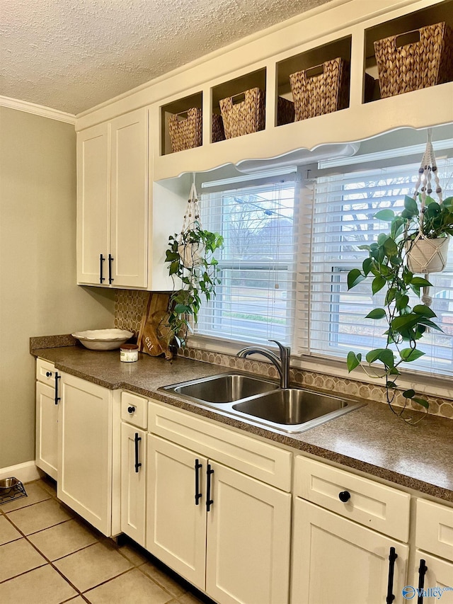 kitchen featuring light tile patterned floors, a textured ceiling, sink, and white cabinets