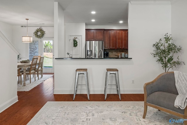 2902 Old Barn Cir SE, Owens Cross Roads, AL 35763 - kitchen with stainless steel fridge, dark countertops, dark wood-type flooring, a kitchen bar, and recessed lighting