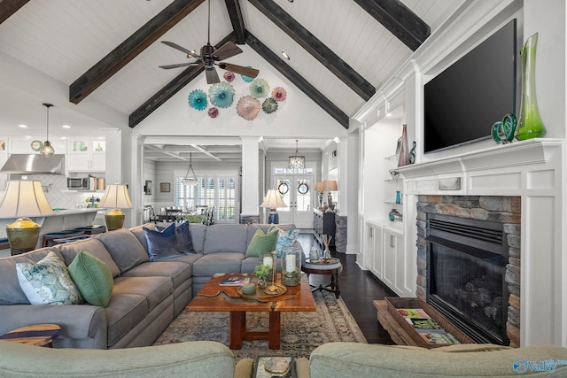 living area with beamed ceiling, a fireplace, dark wood-style flooring, and ornate columns