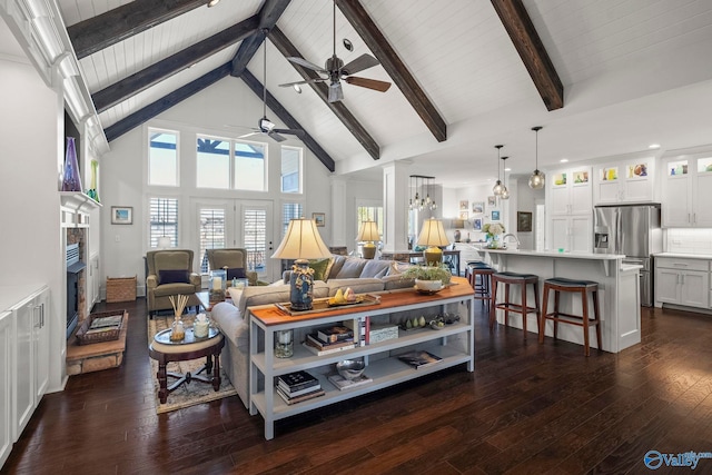 living area featuring ceiling fan, beam ceiling, a fireplace, high vaulted ceiling, and dark wood-style flooring