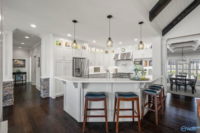 kitchen with under cabinet range hood, backsplash, stainless steel fridge, light countertops, and range