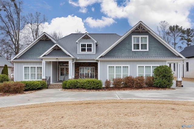 craftsman-style house featuring board and batten siding, covered porch, metal roof, stone siding, and a standing seam roof