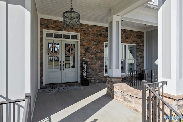 doorway to property with french doors, covered porch, and stone siding