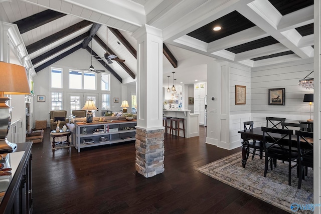 dining space featuring beam ceiling, ceiling fan with notable chandelier, dark wood-type flooring, and ornate columns