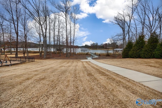 exterior space featuring a lawn, fence, and a water view