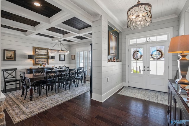 foyer entrance featuring beam ceiling, coffered ceiling, dark wood finished floors, french doors, and an inviting chandelier