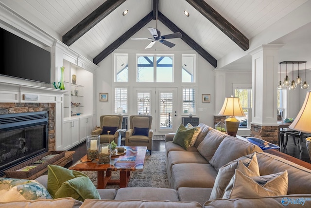 living area featuring beamed ceiling, a fireplace, wood finished floors, high vaulted ceiling, and a ceiling fan