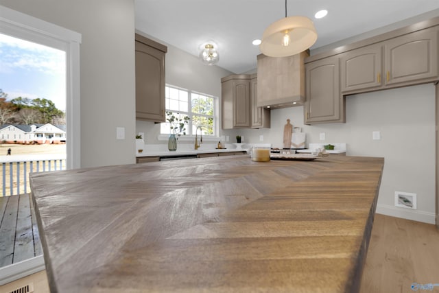 kitchen featuring dishwasher, pendant lighting, light wood-type flooring, and custom range hood