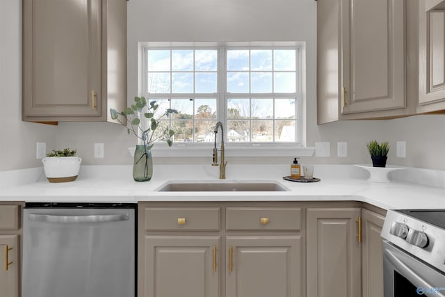 kitchen featuring dishwasher, stove, gray cabinetry, and sink