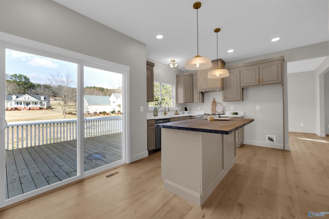 kitchen with dishwasher, decorative light fixtures, a kitchen island, and light hardwood / wood-style floors