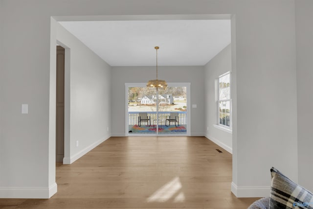 unfurnished dining area with light hardwood / wood-style flooring and an inviting chandelier