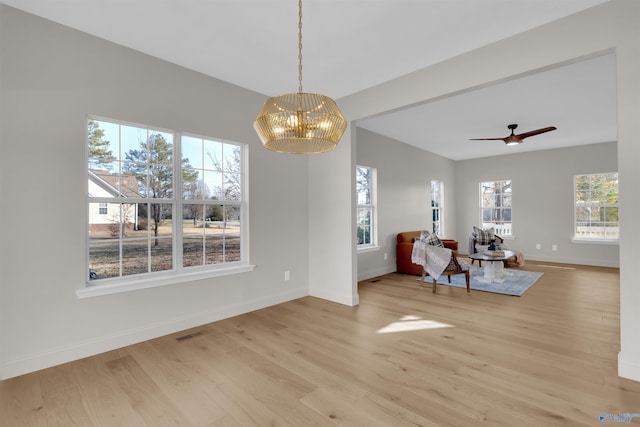 interior space featuring ceiling fan with notable chandelier and light hardwood / wood-style floors