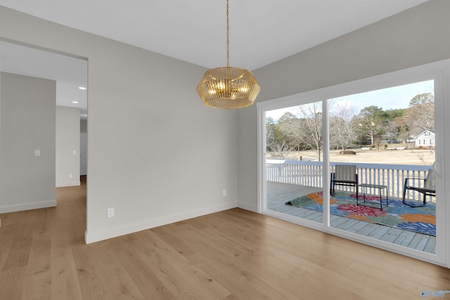 unfurnished dining area with light hardwood / wood-style flooring and a notable chandelier