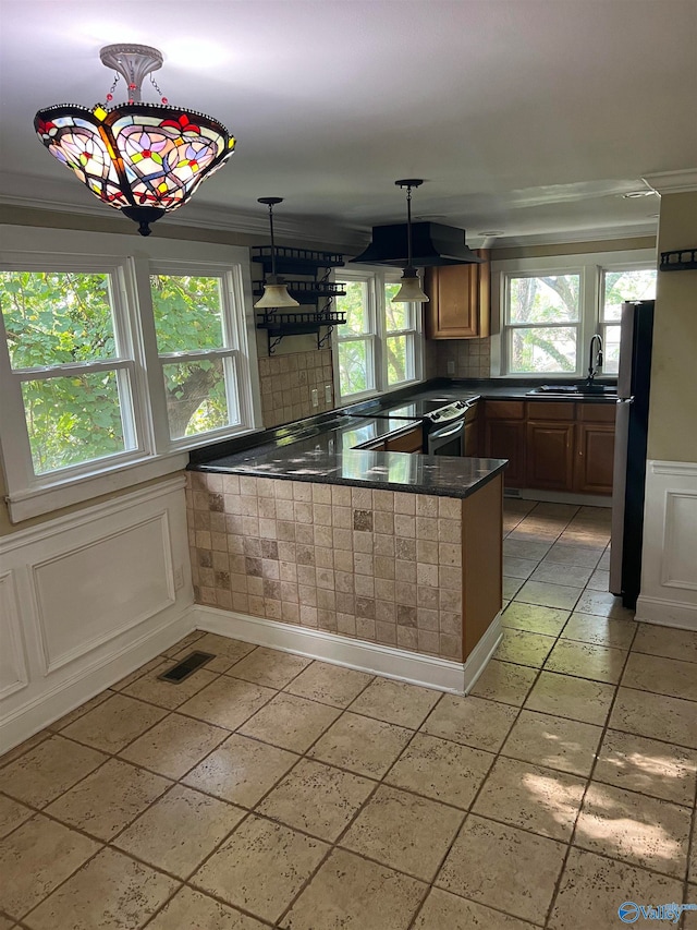 kitchen featuring kitchen peninsula, fridge, decorative light fixtures, crown molding, and sink