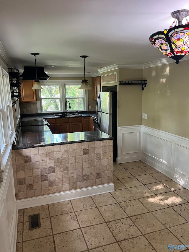 kitchen with pendant lighting, kitchen peninsula, stainless steel refrigerator, sink, and light tile patterned floors