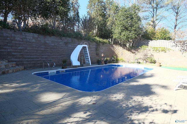 view of swimming pool with a patio area and a water slide