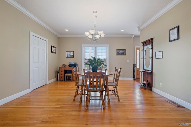 dining area with light hardwood / wood-style flooring, an inviting chandelier, and ornamental molding