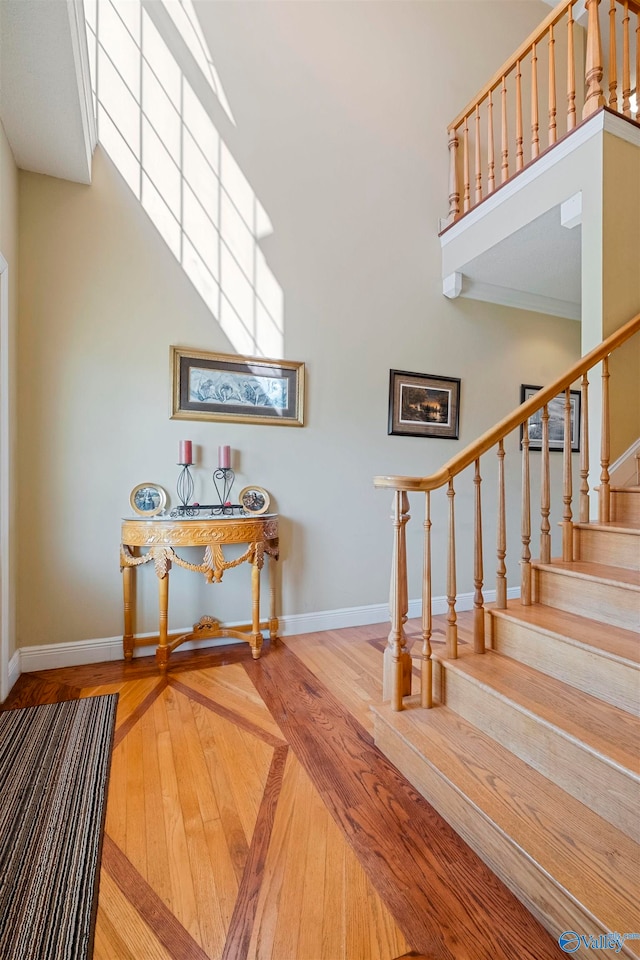 staircase with wood-type flooring and a high ceiling