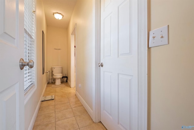 corridor with light tile patterned floors and a textured ceiling