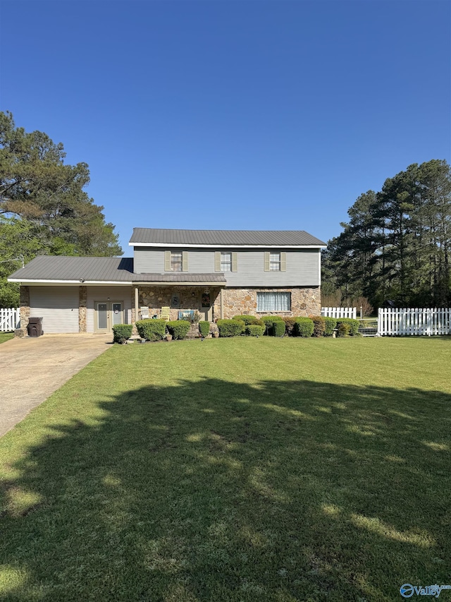 view of front of property featuring concrete driveway, stone siding, a front yard, metal roof, and fence