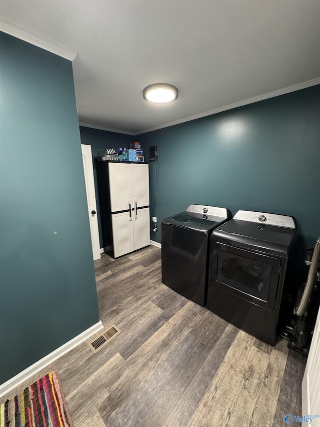 laundry area with visible vents, ornamental molding, laundry area, wood finished floors, and washing machine and clothes dryer