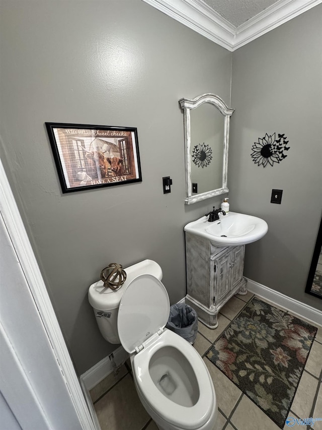 bathroom featuring vanity, ornamental molding, tile patterned flooring, toilet, and baseboards