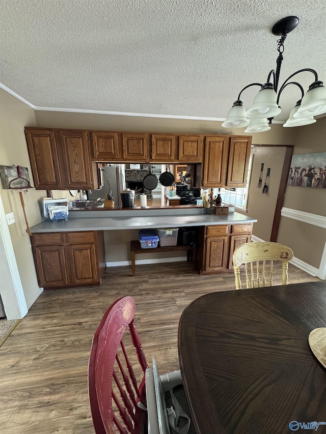 kitchen with crown molding, brown cabinetry, a chandelier, and a textured ceiling