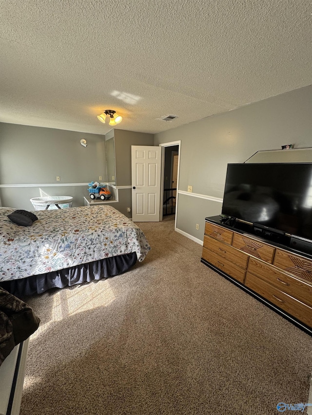 bedroom featuring a textured ceiling, baseboards, carpet, and visible vents
