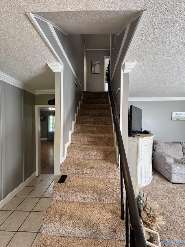 stairway featuring crown molding, tile patterned flooring, and a textured ceiling