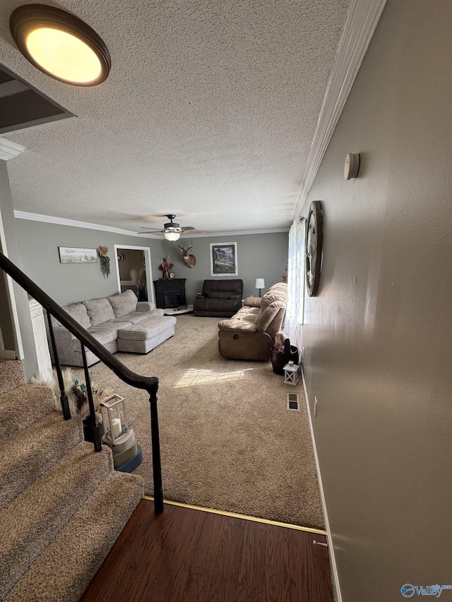 living area featuring stairs, visible vents, crown molding, and ceiling fan
