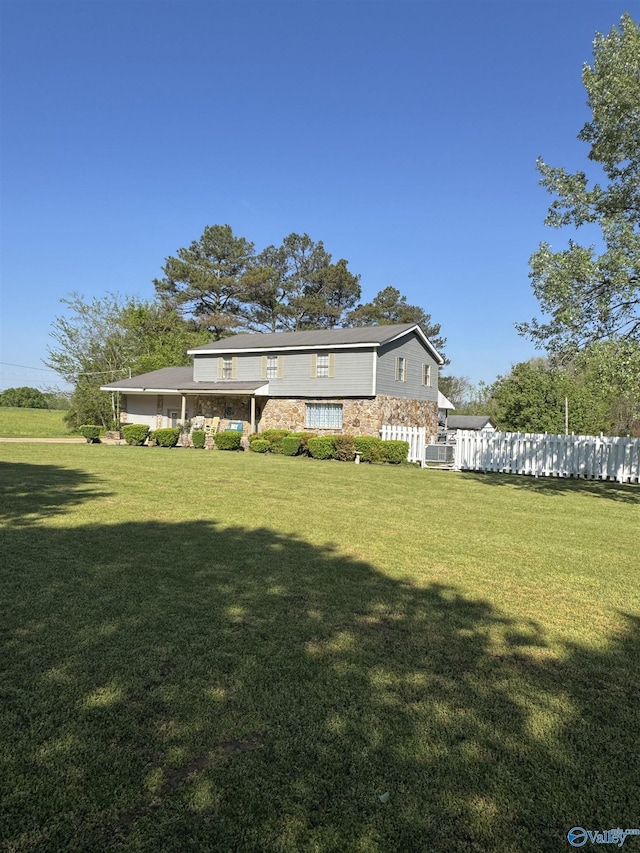 exterior space with stone siding, fence, and a lawn