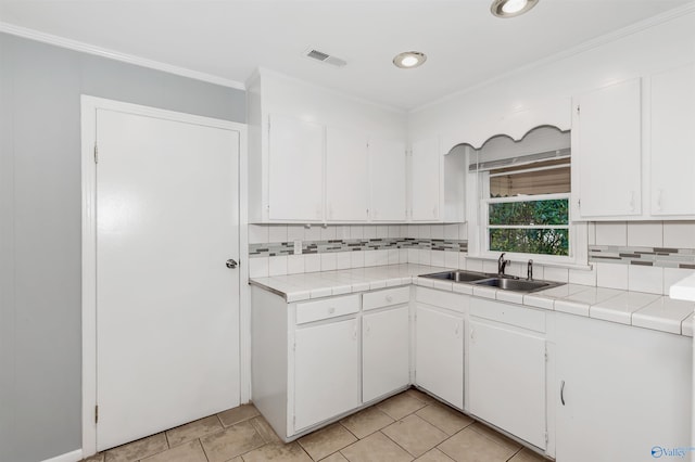 kitchen featuring tile counters, visible vents, white cabinetry, and a sink