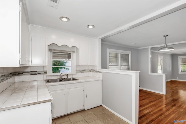 kitchen with backsplash, tile countertops, white cabinetry, and a sink