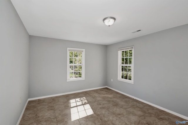 spare room featuring visible vents, plenty of natural light, and baseboards