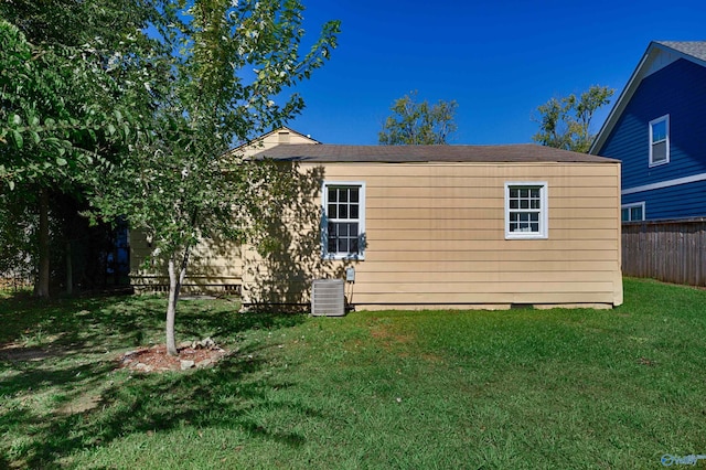 back of property with a yard, central air condition unit, and fence