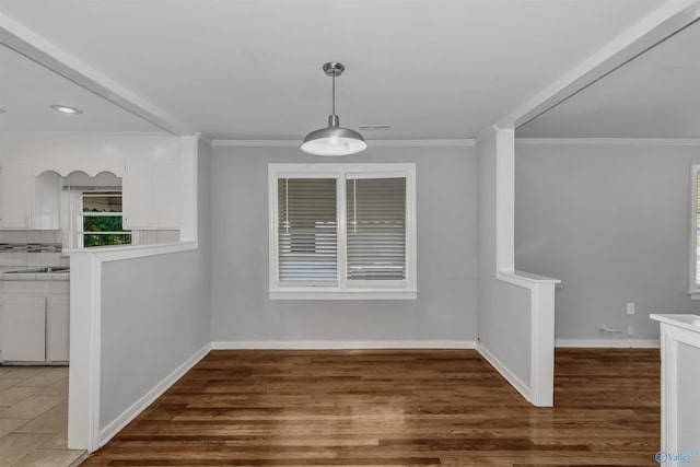 unfurnished dining area with visible vents, wood finished floors, baseboards, and ornamental molding