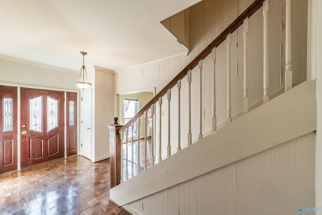 foyer entrance featuring crown molding and parquet flooring