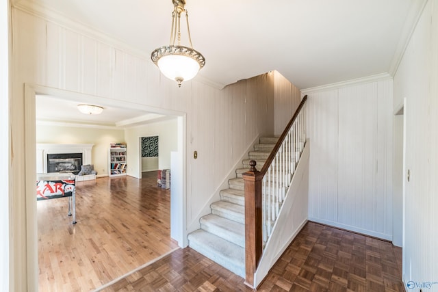 staircase featuring crown molding and parquet flooring