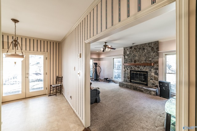 living room featuring a stone fireplace, light carpet, ceiling fan, and french doors