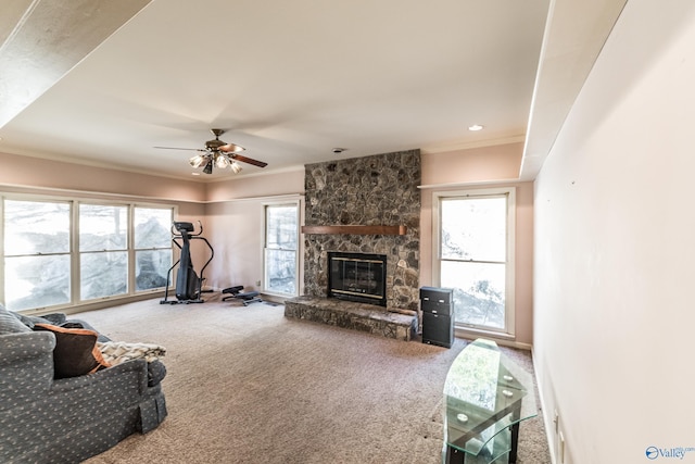 carpeted living room featuring crown molding, ceiling fan, and a fireplace