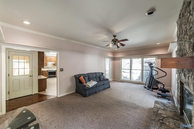 carpeted living room featuring ornamental molding, ceiling fan, and a fireplace