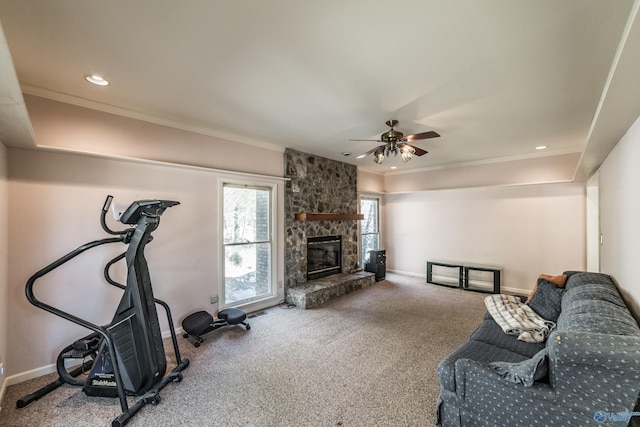 living room with ornamental molding, carpet, ceiling fan, and a fireplace