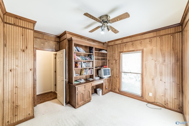 carpeted home office with ornamental molding, ceiling fan, and wood walls