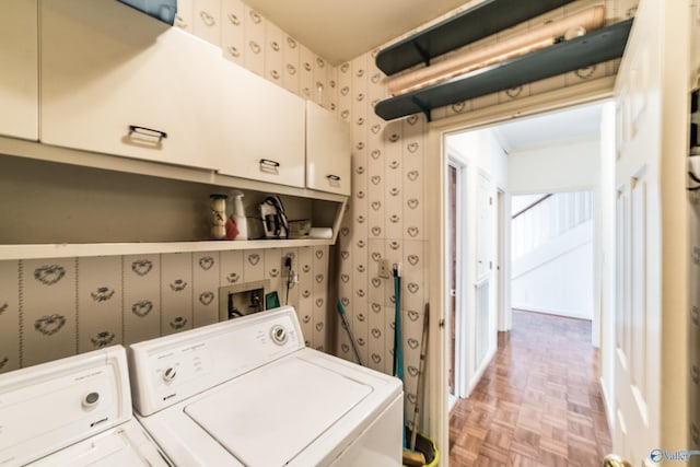 clothes washing area featuring cabinets, light parquet flooring, and washing machine and clothes dryer