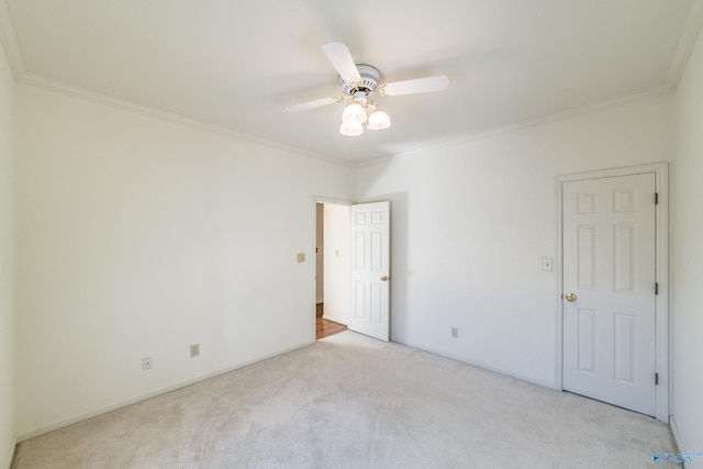 spare room with crown molding, ceiling fan, and light carpet