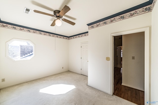 unfurnished bedroom featuring ceiling fan, light colored carpet, and crown molding