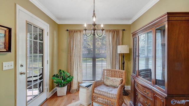 living area featuring a notable chandelier, light wood-type flooring, baseboards, and ornamental molding
