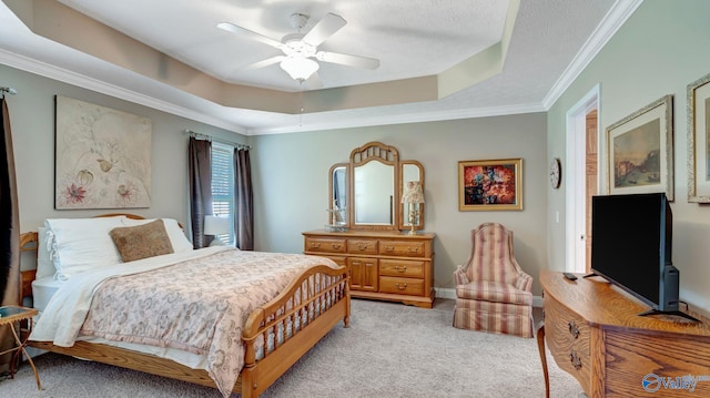 bedroom featuring a tray ceiling, light colored carpet, crown molding, and a ceiling fan