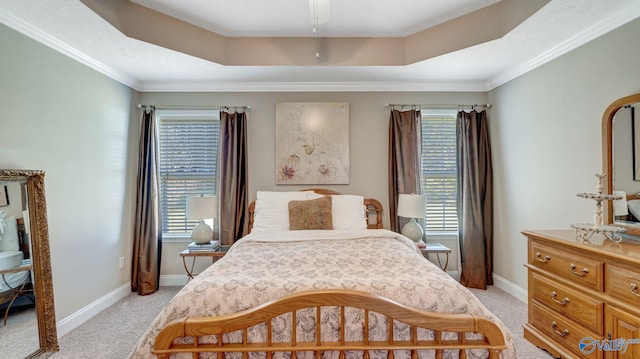 bedroom featuring light carpet, baseboards, crown molding, and a tray ceiling