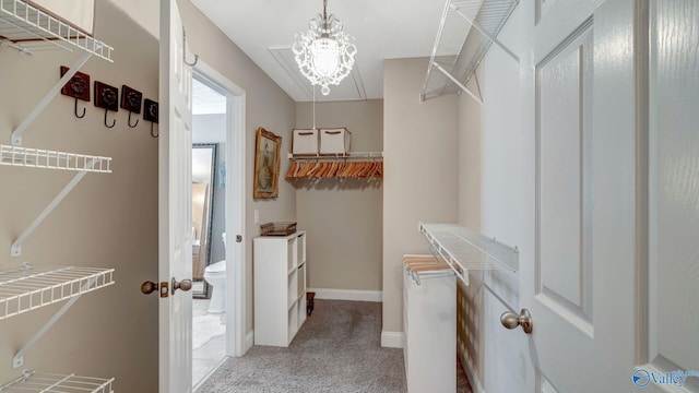 walk in closet with light carpet and a chandelier